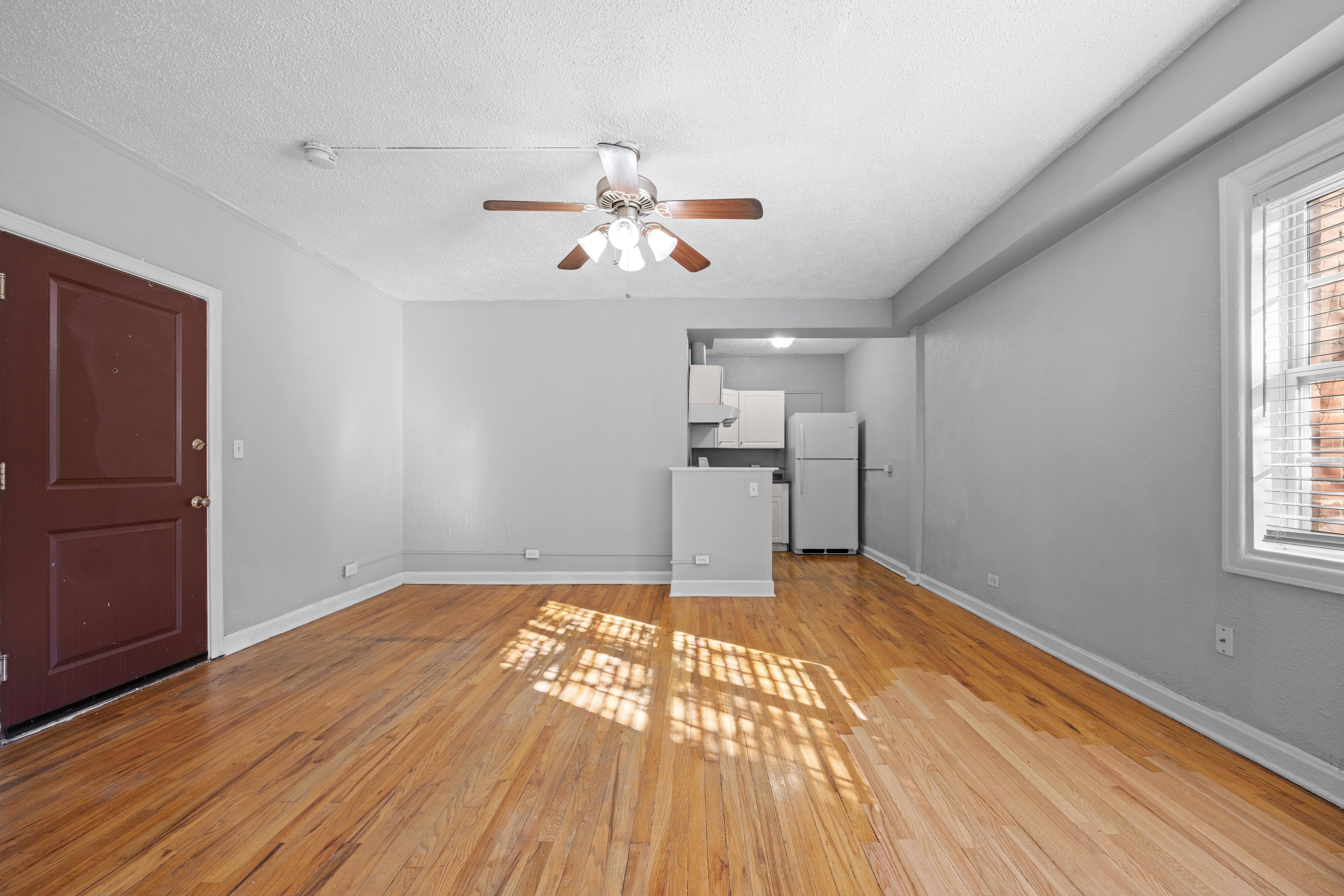 A room with a ceiling fan and wooden floors.